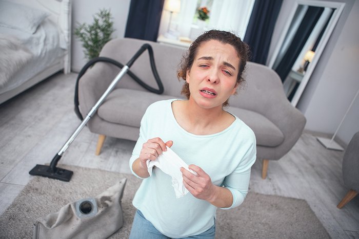 Frau, die beim Putzen allergisch reagiert
